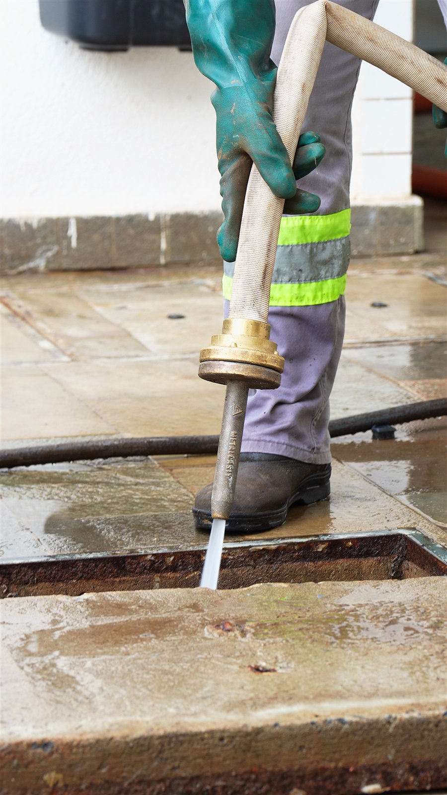 Profissional realizando hidrojateamento com equipamento de alta pressão